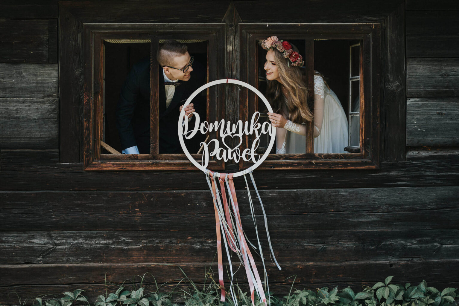 Para młoda wygląda przez okno chatki w skansenie w Opolu