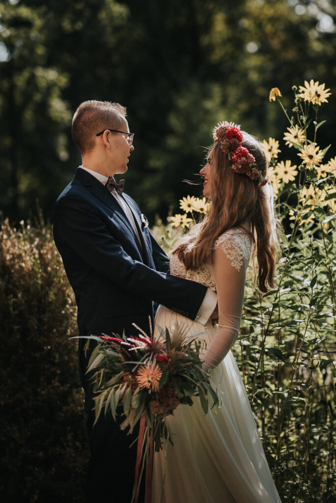 Para młoda pozuje na tle kwiatów w ogrodzie Muzeum Wsi Opolskiej