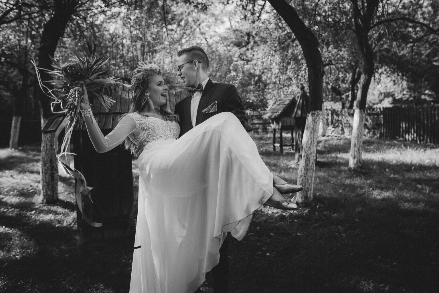 Noszona na rękach panna młoda w ogrodzie Muzeum Wsi Opolskiej