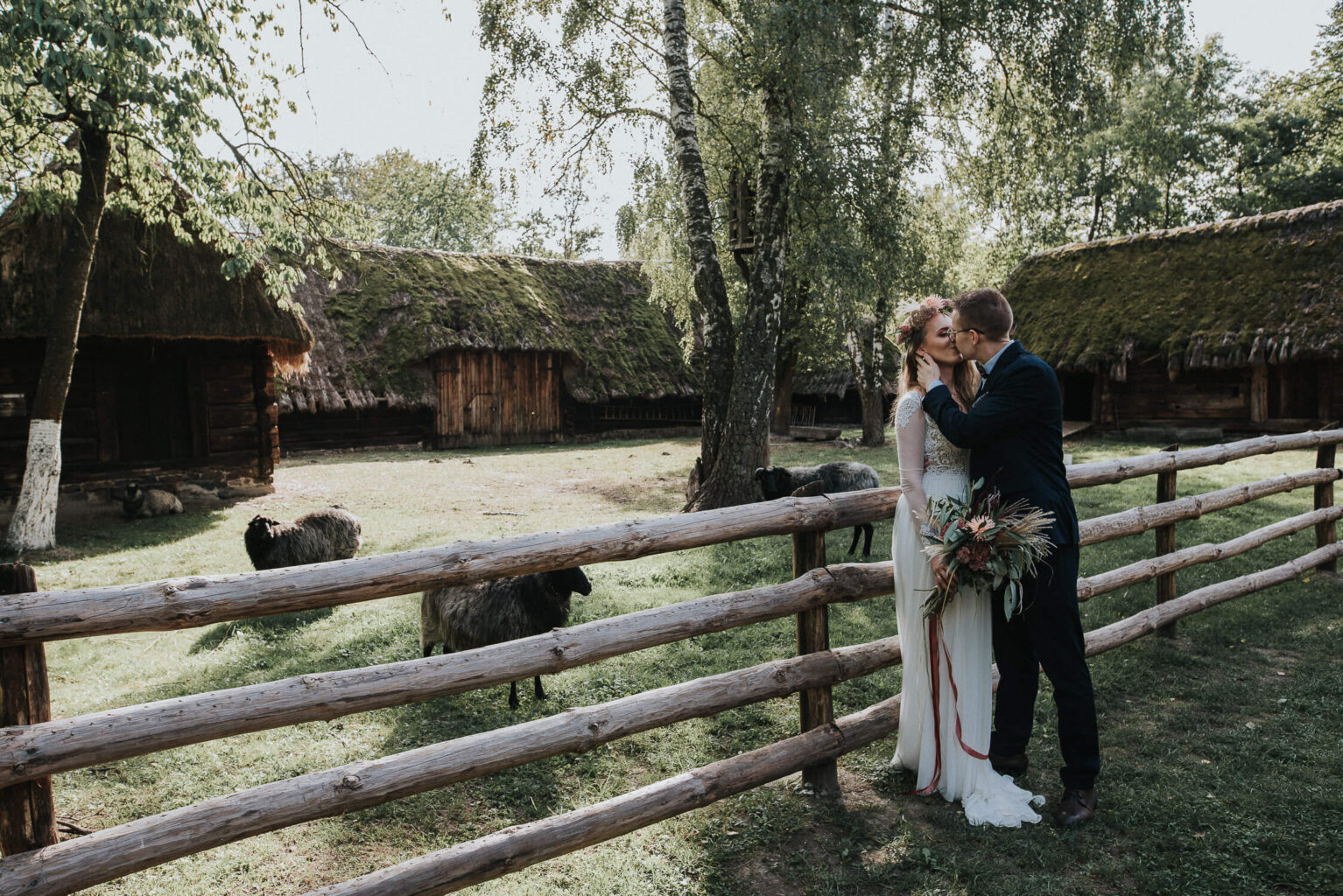 Para młoda całuje się na tle zagrody z owcami w skansenie w Opolu