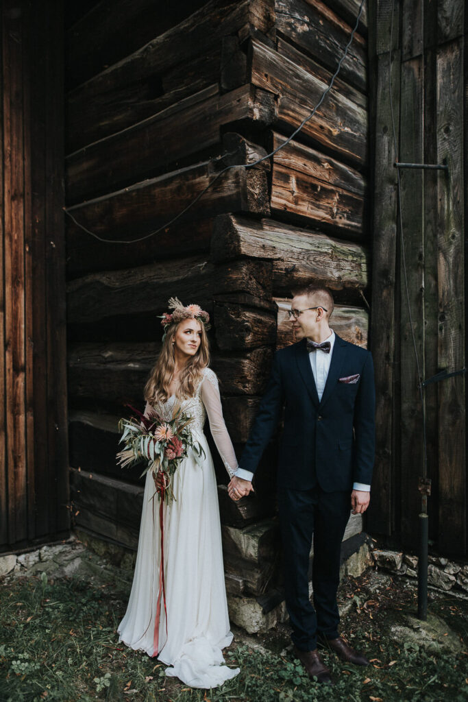 Para młoda pozuje na tle ściany starego kościoła w Muzeum Wsi Opolskiej