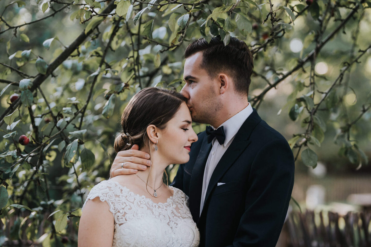 Para młoda pozuje na tle jabłoni w skansenie w Opolu podczas rustykalnej sesji zdjęciowej