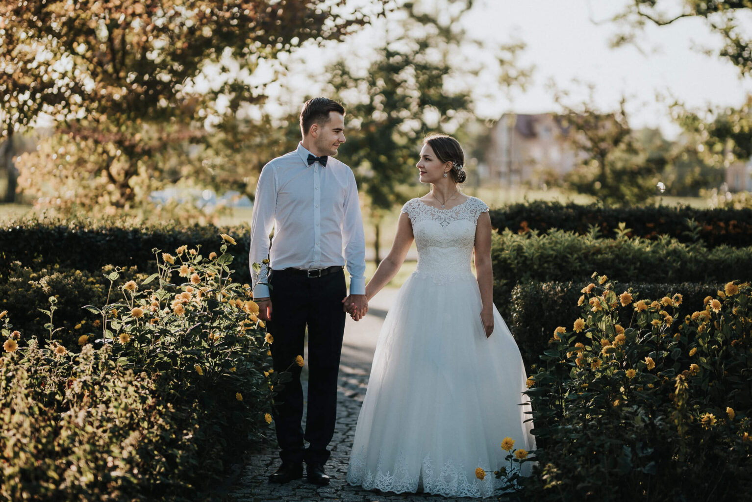 Para młoda uśmiech się do siebie w czasie rustykalnej sesji zdjęciowej w skansenie