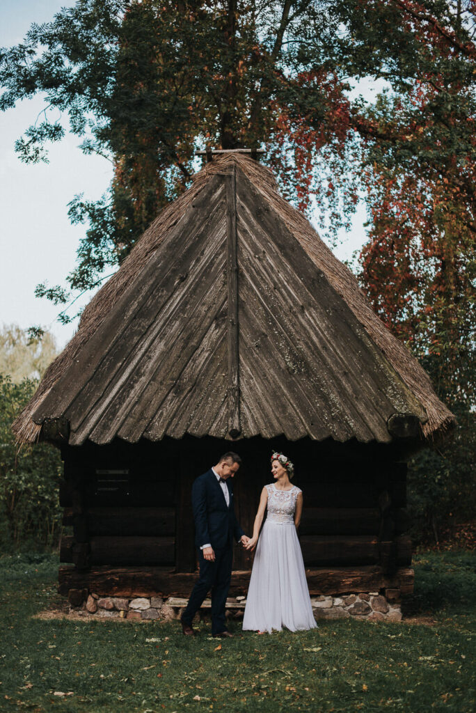 Para młoda pozuje na tle zabudowy Muzeum Wsi Opolskiej podczas rustykalnej sesji zdjęciowej